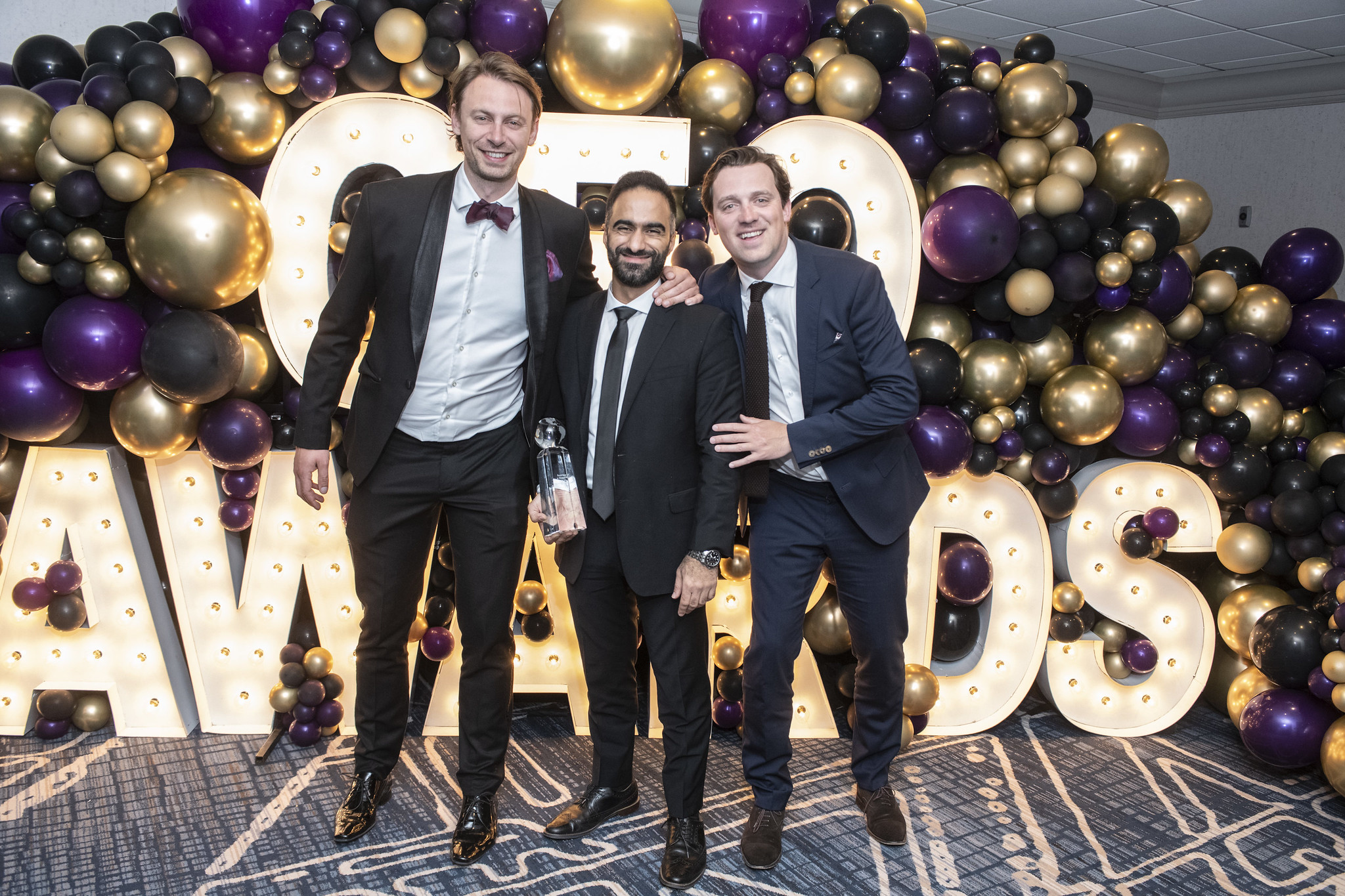 Three winners standing with award in hand